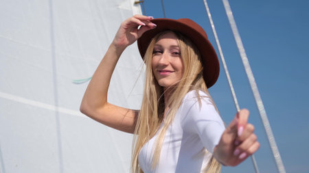 Attractive blonde woman sails on a yacht with a sail on a sunny summer dayの写真素材