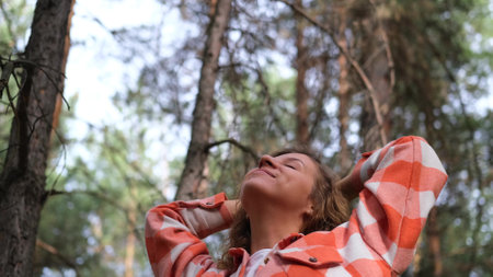A young woman breathes clean air, looks at the sky with a smile, walks with pleasure in the autumn...