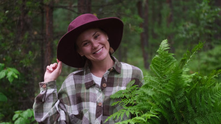 A young woman breathes clean air, looks at the sky with a smile, walks through the forest with...
