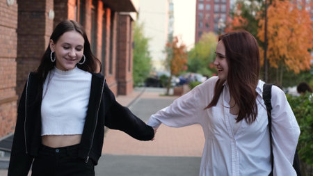 Cute teenage friends walking down the street together and holding hands