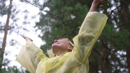 Portrait of a woman in the forest during the rain. A young woman in a yellow protective raincoat...
