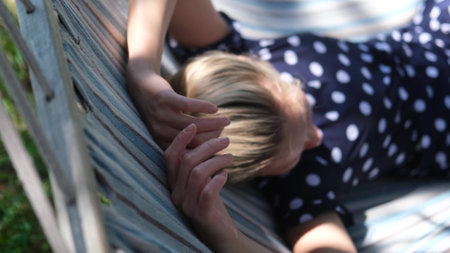 Pretty woman is resting in a hammock in summer near the river during vacation. Woman resting in the shade on a hot afternoon afternoonの写真素材