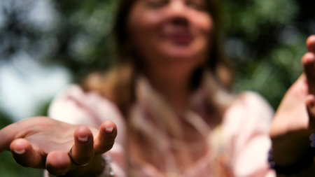 A young woman raises her hands up, the woman is wearing a pink long dress in boho style. A woman is enjoying the beautiful weather. She thanks God for her life and a beautiful day.の写真素材
