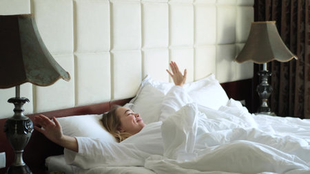 Pretty happy woman waking up in bed at home enjoying her vacation. Beautiful caucasian woman is resting on the bed. Sleep and rest conceptの写真素材