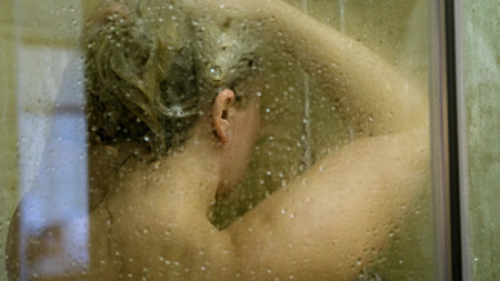 Womens hair care. A woman stands under the shower, washing her long hair covered with foam.の写真素材