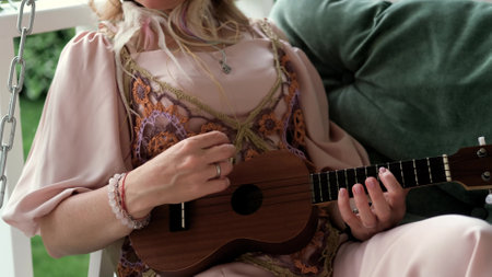 A woman in an elegant boho style dress plays the ukulele.の写真素材