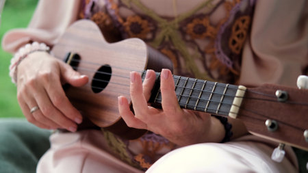 A woman in an elegant boho style dress plays the ukulele.の写真素材
