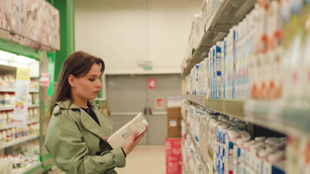 Young woman chooses dairy products in a supermarketの写真素材