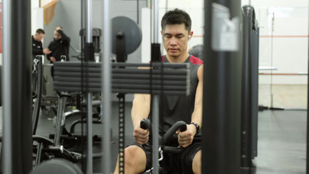 A man does exercises on the simulators in the gym. Exercise Press hands, sitting in the simulator.
