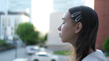 Happy teenage girl enjoys a beautiful day, breathes fresh air in the city streetの写真素材