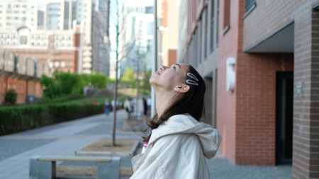 Happy teenage girl enjoys a beautiful day, breathes fresh air in the city streetの写真素材