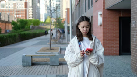 A sad girl is waiting for a friend who is late for a meeting. Teenager looking back on street with urban backgroundの写真素材