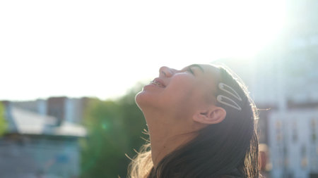 Happy teenage girl enjoys a beautiful day, breathes fresh air in the city streetの写真素材