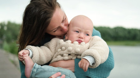 A woman and a little boy on a walk by the river. Mother holds her son in her arms.