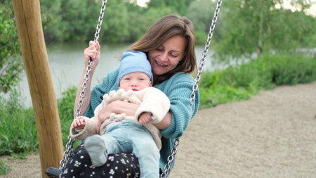 A young mother and a small child are swinging on a swing. Open. Childrens Day concept.の写真素材