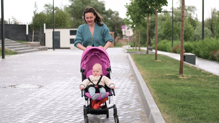 A young mother walks with a baby in a stroller in the city street