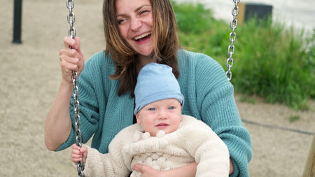 A young mother and a small child are swinging on a swing. Open. Childrens Day concept.の写真素材