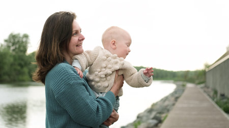 A woman and a little boy on a walk by the river. Mother holds her son in her arms.