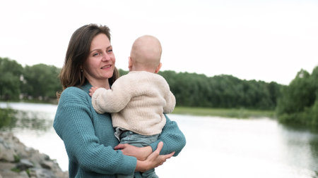 A woman and a little boy on a walk by the river. Mother holds her son in her arms.