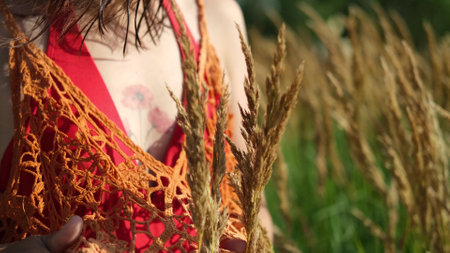 Happy free asian woman walking in tall grass on a sunny summer day. Portrait of a hippie woman in a bright orange boho style topの写真素材