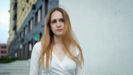 Photo of a beautiful young teen girl in long hair standing against a white wallの写真素材