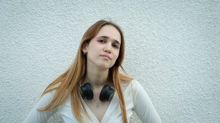 Photo of a beautiful young teen girl in long hair standing against a white wallの写真素材