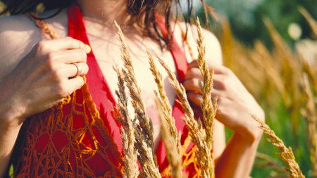 Happy free asian woman walking in tall grass on a sunny summer day. Portrait of a hippie woman in a bright orange boho style topの写真素材