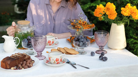 A woman with a cup of fresh green tea with mint and sea buckthorn sits at a table in the fresh air...