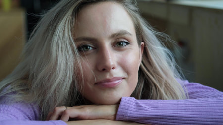Beautiful young blonde woman smiling and looking at the camera. Woman looking relaxed, friendly and...