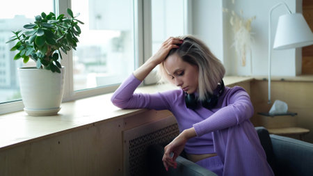 Beautiful blonde woman with purple house suit looks relaxed at homeの写真素材