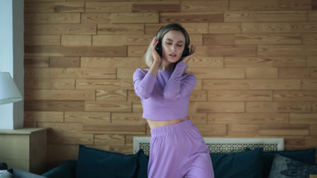 Cute beautiful blonde girl in homemade purple costume dancing at home, enjoying relaxation, happy...