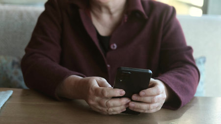 A middle-aged woman with glasses reads the news on a smartphone, makes purchases online using a store app.の写真素材