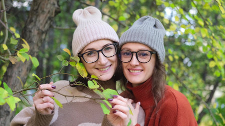 Two women friends or sisters hugging outdoors in autumn parkの写真素材