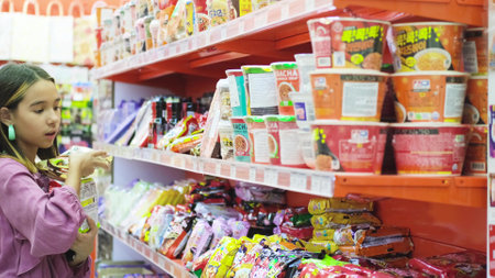 Russia, Novosibirsk, 11.11.2023: Black Friday. Discounts in retail stores. A little girl chooses food and sweets in stores selling products from China.のeditorial素材