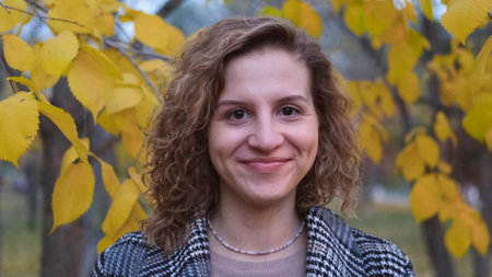 Portrait of a woman outdoors enjoying nature. Young woman with curly hair in an autumn park in the...