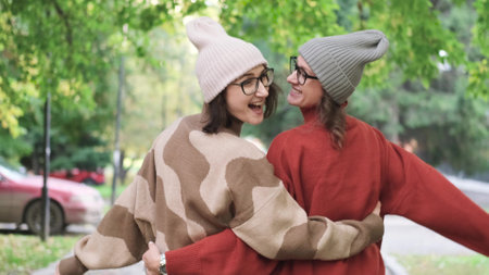 Two women friends or sisters hugging outdoors in autumn parkの写真素材