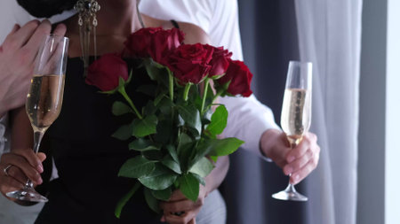 A very beautiful smiling woman hugs her husband and holds red roses and a gift given to her for Valentines Day.の写真素材