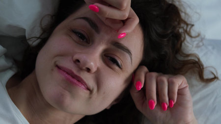 Young woman sleeping in bed. Portrait of a beautiful woman resting on a comfortable bed with pillows in white bedding in the bedroom in the morning. High quality image.の写真素材