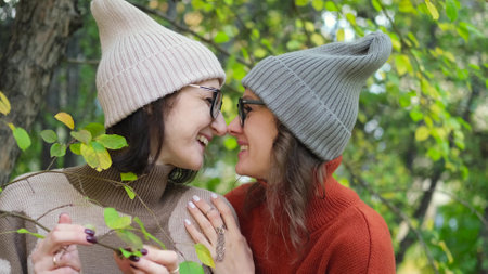 Two girlfriends are walking and having fun outside among autumn trees in a city park.の写真素材