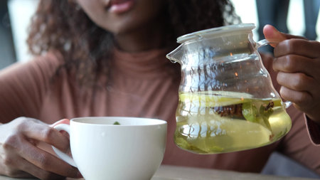 Female hands pour hot fruit tea into a cup in the morning during the cold season
