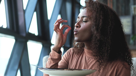 Such delicious tasty filling food. Close-up of a curly-haired beautiful woman tasting food in a new...