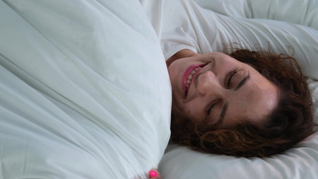 Young woman sleeping in bed. Portrait of a beautiful woman resting on a comfortable bed with pillows...