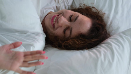 Young woman sleeping in bed. Portrait of a beautiful woman resting on a comfortable bed with pillows in white bedding in the bedroom in the morning. High quality image.の写真素材