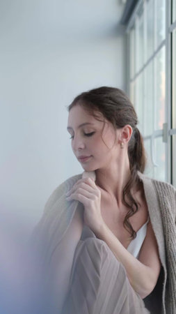 Beautiful young girl posing for the camera while sitting near a large window