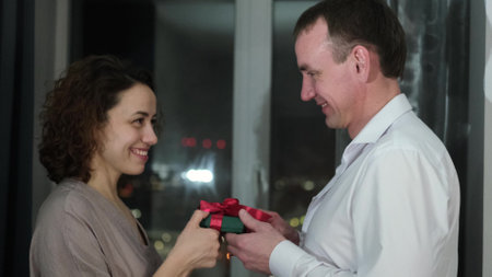 Happy Valentines Day. A man gives his beloved woman a gift. Husband gives his wife pleasant surprisesの写真素材