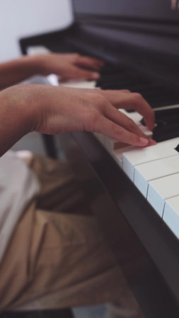 Close-up of a teenage pianists hands. A teenager plays the piano, touching the black and white keys...