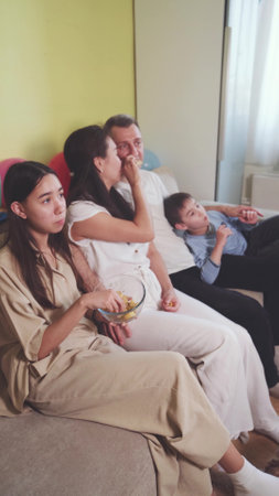 Family sitting on the couch at home and watching TVの写真素材