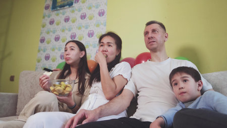 Family sitting on the couch at home and watching TV