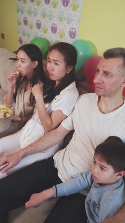 Family sitting on the couch at home and watching TV