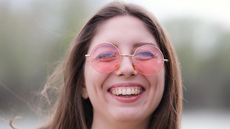 Happy woman in pink sunglasses outdoors smilingの写真素材